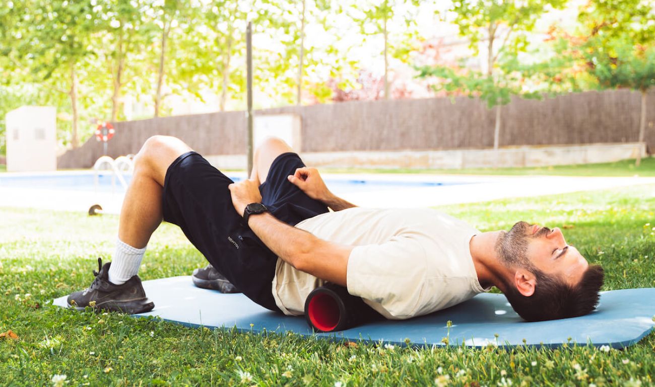 Hombre jóven estirando al aire libre con una esterilla