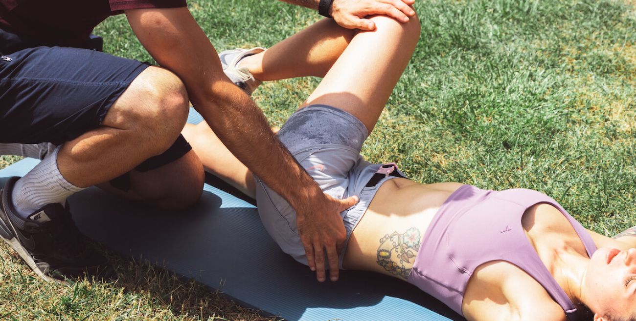 mujer estirando la espalda en casa con ayuda de entrenador