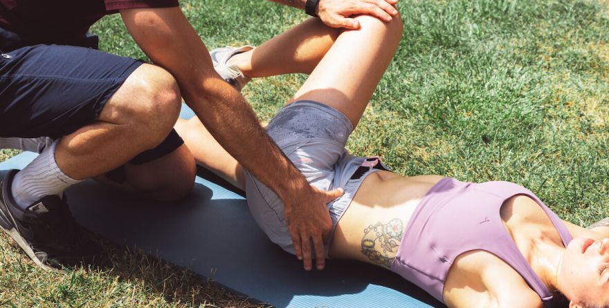 mujer estirando la espalda en casa con ayuda de entrenador